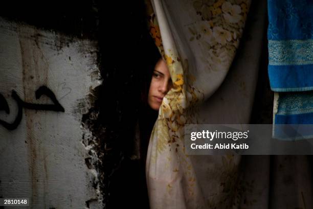 Palestinian woman looks at the supporters of the Islamic Hamas movement as they attend a demonstration in the southern Gaza Strip refugee camp of...