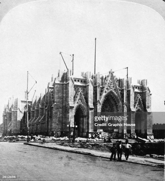 View of three men posing outside St. Patrick's Cathedral at 5th Avenue and 51st Street as it is under construction, New York City, circa 1875.