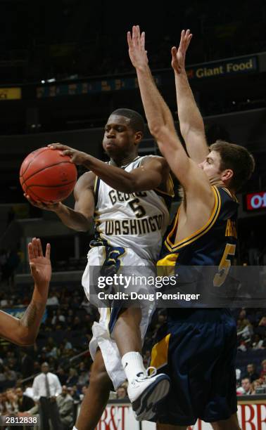 Thompson of the George Washington Colonials passes the ball around Joe Herber of the West Virginia University Mountaineers during the BB&T Classic...