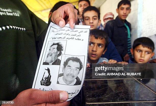 Iraqis in the town of Fallujah, 50 kms west of Baghdad, show a pamphlet distrubuted 16 Decembre 2003, announcing the capture of wanted former...