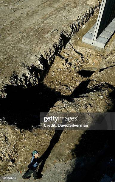 Palestinian boy passes where Israel is building its security wall December 16, 2003 between the West Bank Palestinian village of Nazlat Issa and the...