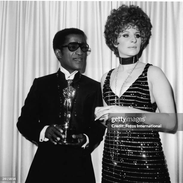 American singer and actor Sammy Davis Jr. Stands with presenter Barbra Streisand, holding the Oscar for Best Song, at the Academy Awards ceremony,...