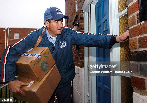 Postal Service carrier Ron Comly carries parcel packages to a home while delivering mail along his postal route December 17, 2003 in Philadelphia,...