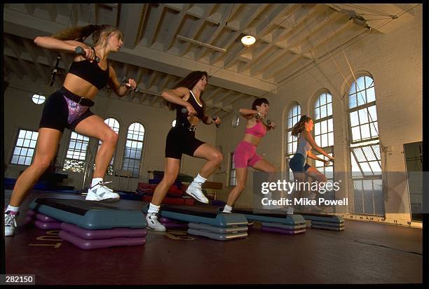 A GROUP OF MODEL RELEASED WOMEN DO A STEP AEROBICS WORKOUT.