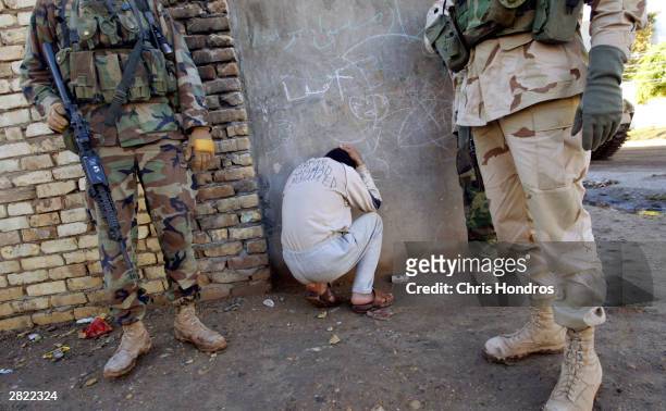Bound Iraqi informer, with his name inked in English across his back, crouches beside soldiers in the 4th Infantry Division after providing outdated...
