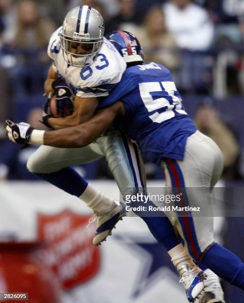 Terry Glenn of the Dallas Cowboys makes a pass reception while tackled by Dhani Jones of the New York Giants on December 21, 2003 at Texas Stadium in...