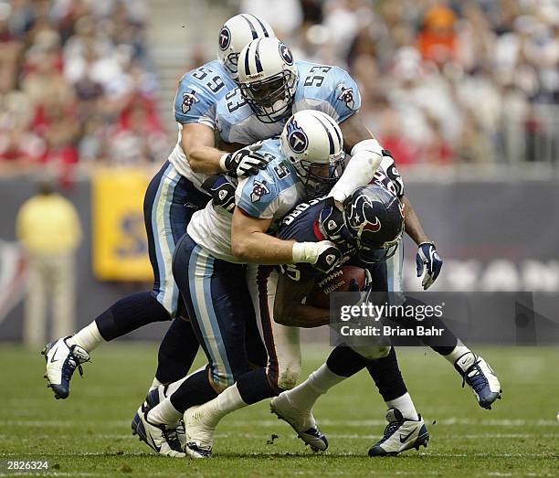 Linebackers Brad Kassell, Keith Bullock, Peter Sirmon of the Tennessee Titans pile up on wide receiver Corey Bradford of the Houston Texans December...