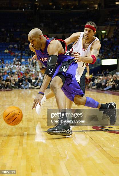 Vince Carter of the Toronto Raptors drives by Ira Newble of the Cleveland Cavaliers during the game at Gund Arena on December 9, 2003 in Cleveland,...