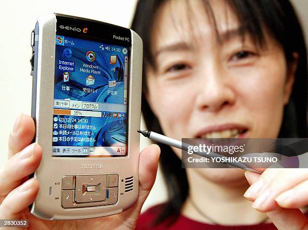 Japan's electronics giant Toshiba employee Junko Furuta displays the thin and light PDA "Genio e400", equipped with Intel's 300MHz-PXA263 processor...