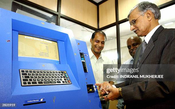 State Bank of Mysore Managing Director M. Sitarama Murty puts Indian paper currency into "KUBERA"-an automated stamp duty collecting machine at an...