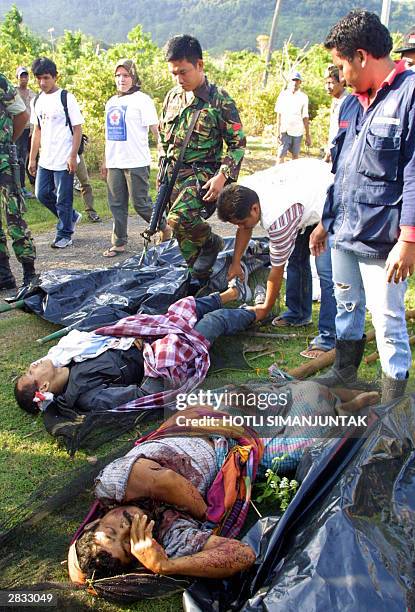 Acehnese and government soldiers evacuate two wounded Free Acehnese Movement's rebels after gunfire at Ujong Pancu in Aceh Besar 27 December 2003....