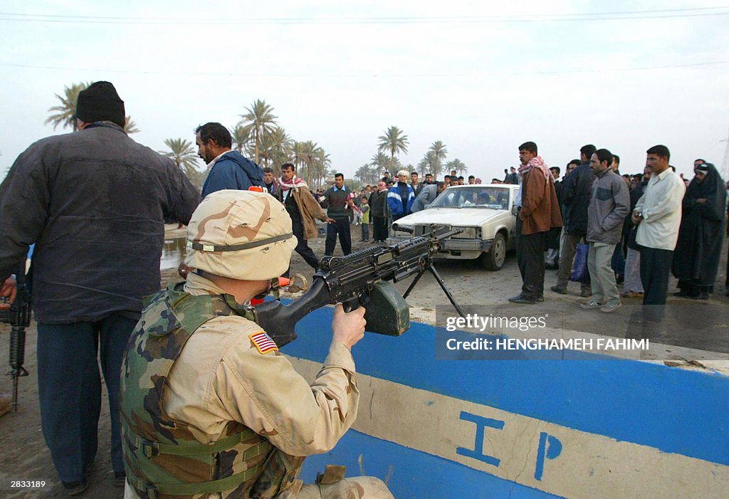 A US soldier sits behind a cement barrie