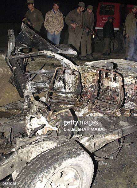 Afghan policemen stand guard beside the wreckage of a car at a bomb blast site near to Kabul International Airport, 28 December 2003. Six people were...