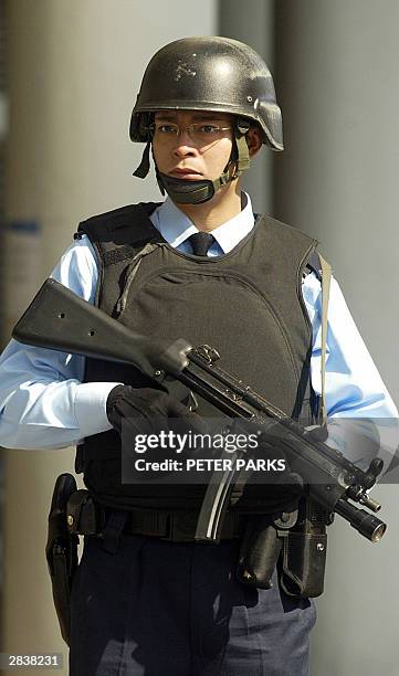 Heavily armed policeman stands guard outside Eastern Court as Hong Kong's most wanted man, Kwai Ping-hung appears for a hearing, 31 December 2003....
