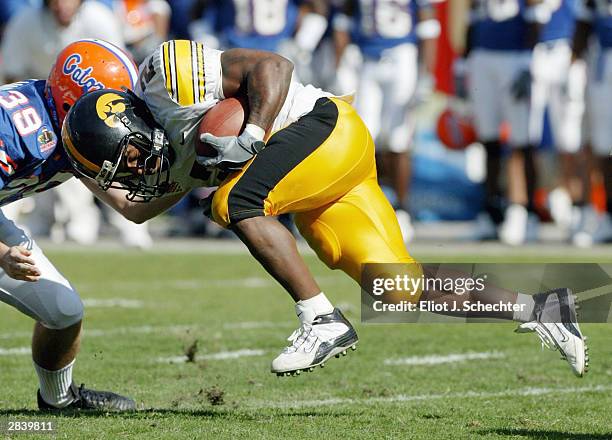 Runningback Fred Russell of the Iowa Hawkeyes tangles with Kicker Chris Hetland of the Florida Gators in the Outback Bowl January 1, 2004 at Raymond...