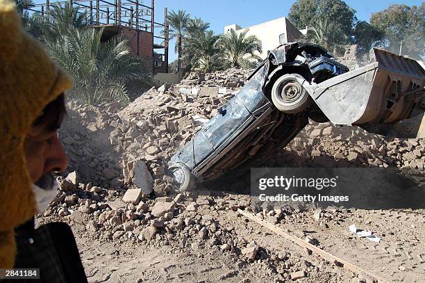 Man watches as a heavy machine pulls a car from a pile of rubble January 2, 2003 in Bam, Iran. A week after a massive earthquake shattered Bam,...