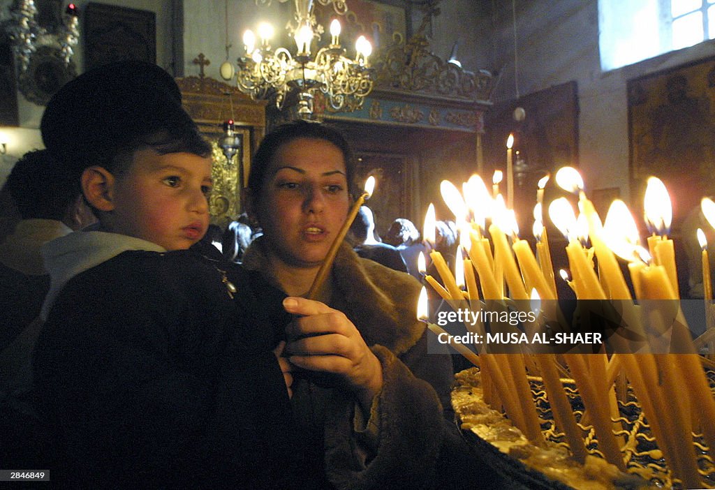 A Greek Orthodox woman lights candles wi