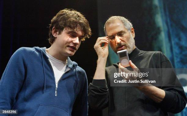 Apple CEO Steve Jobs looks at a new iPod mini with recording artist John Mayer at the Macworld expo January 6, 2004 in San Francisco. Jobs announced...