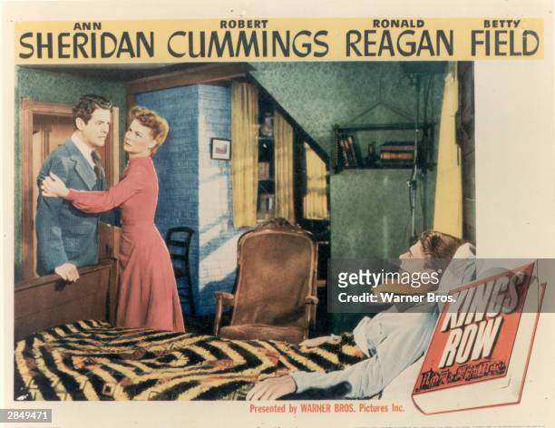 American actor Ann Sheridan restrains American actor Robert Cummings , while American actor and politician Ronald Reagan, as an invalid, lies in bed...