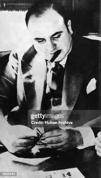 American gangster Al Capone plays cards in a train compartment during his transport to prison to serve a sentance for tax evasion, October 1931.