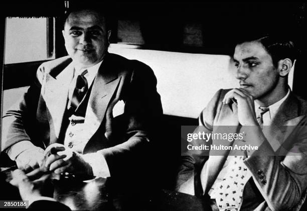 American gangster Al Capone sits in a train compartment with an unidentifed associate during his transport to prison to serve a sentance for tax...