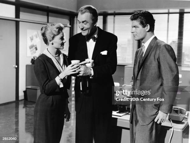 American actor Hope Lange takes a paper cup from British actor Brian Aherne , who also holds a bottle, while Irish actor Stephen Boyd stands nearby...