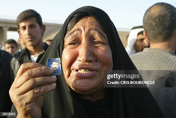 An Iraqi woman shows a picture of her son she believes is jailed at Abu Gharib prison, 35km west of Baghdad, as she waits for his release 08 January...