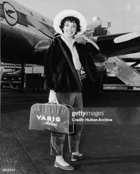 American author Rona Jaffe stands on the tarmac in front of a Varig Airlines plane at Idlewild Airport following the completion of filming 1959's...