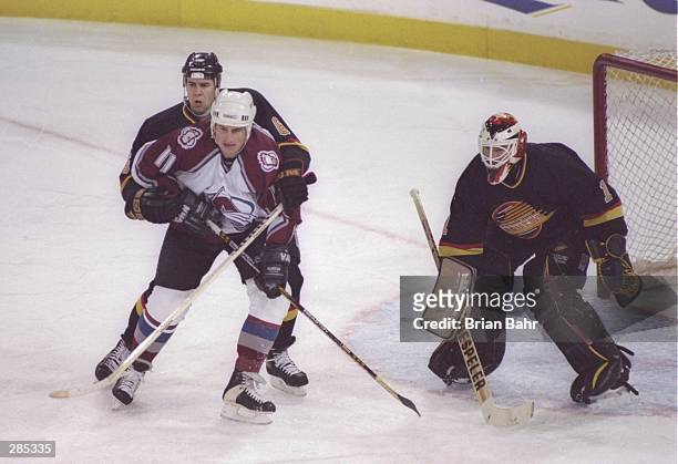Right wing Keith Jones of the Colorado Avalanche tries to free himself from the hands of defensemen Adrian Aucoin of the Vancouver Canucks as fellow...
