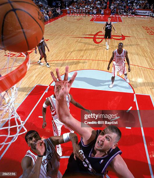 Greg Ostertag of the Utah Jazz and Jim Jackson of the Houston Rockets go up for a rebound during the game on January 3, 2004 at the Toyota Center in...