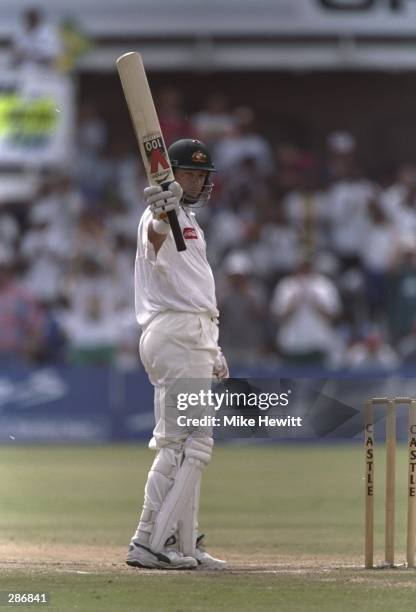 Mark Waugh of Australia holds up his bat after reaching 100 runs during the second test match against South Africa at Port Elizabeth, South Africa....