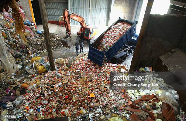 Dumper truck unloads as workers check through products made from U.S imported beef in front of trash burner on January 16, 2004 in Incheon, South...