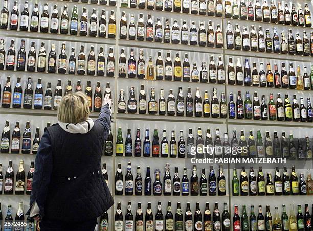 Woman arranges a shelf with hundreds of beer bottles on the stand of German Brewers federation presenting 580 brands of beer, 15 January 2004 in...