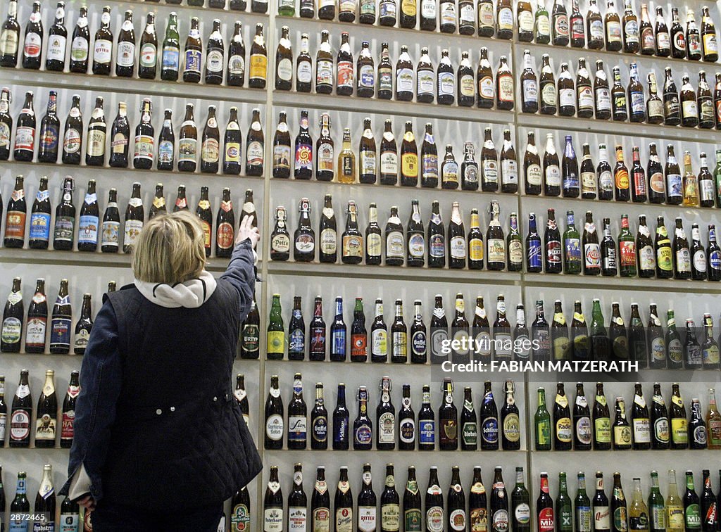 A woman arranges a shelf with hundreds o