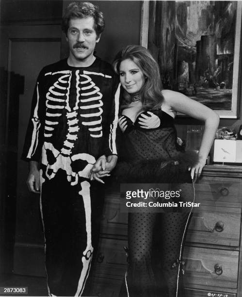 American actors George Segal and Barbra Streisand hold hands, wearing Halloween costumes, in a still from the film, 'The Owl And The Pussycat,'...