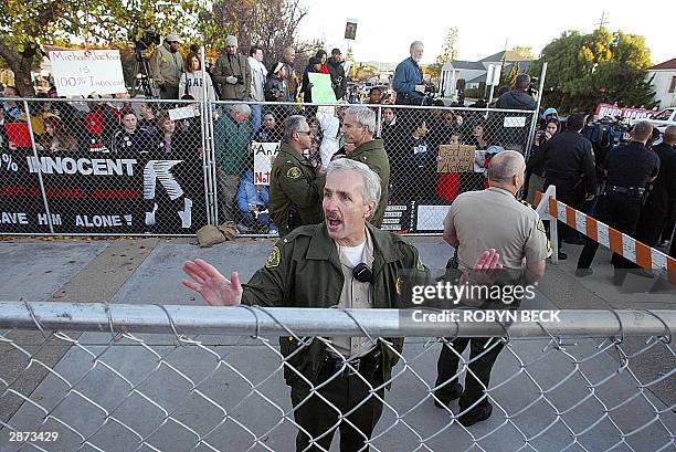 Sheriff's deputy warns fans not to push on the unsecured fence which makes an arrival area for Michael Jackson outside the courthouse in Santa Maria,...