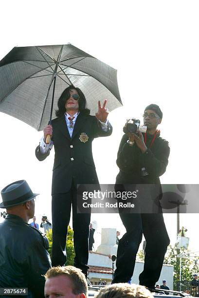 Singer Michael Jackson greets fans from the top of his car following his arraignment on child molestation charges on January 16, 2004 in Santa Maria,...