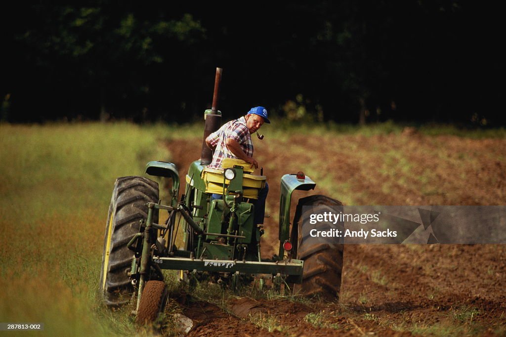 Man in tractor ploughing field, rear view