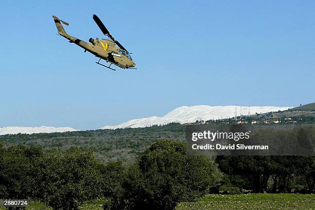 An Israeli Air Force cobra attack helicopter flies on a training mission January 19, 2004 in front of the slopes of the snow-covered Mt. Hermon close...