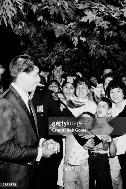 American comedian and actor Jerry Lewis walks past fans wanting autographs outside Keith's Theater, Richmond Hill, New York, 1961.