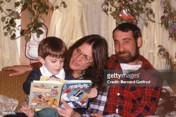 American actor Linda Lovelace , star of 'Deep Throat' reads to her son with her husband, Larry, 1986.