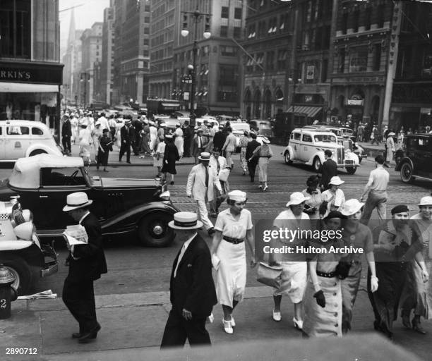 View of pedestrian and vehicle traffic at the intersection of 42nd Street and 5th Avenue, New York, New York, circa 1930. The spire of St. Patrick's...