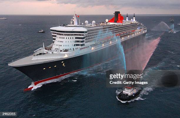 In this handout photo provided by Cunard Line, water-squirting tugboats salute the Queen Mary 2, the largest luxury ocean liner ever constructed, as...