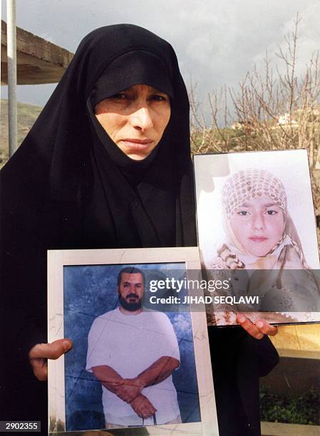 Lebanese Shiite Muslim Fadila carries pictures of her husband Jawad Qasfi, a prisoner held in Israel, and late daughter Jamila, at hers home in the...