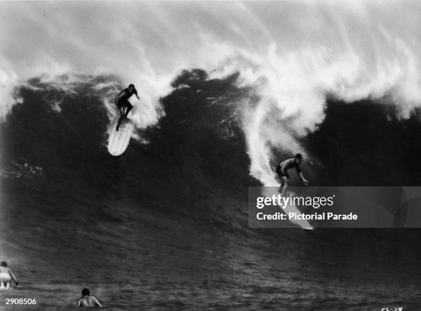 Two surfers ride a large wave in Waimea Bay, Hawaii in a still from the international surfing documentary, 'The Endless Summer,' directed by Bruce...