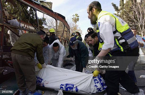 Israeli emergency personnel remove a body from the wreckage after a suicide bomber blew himself up on a bus January 29, 2004 in Jerusalem, Israel....