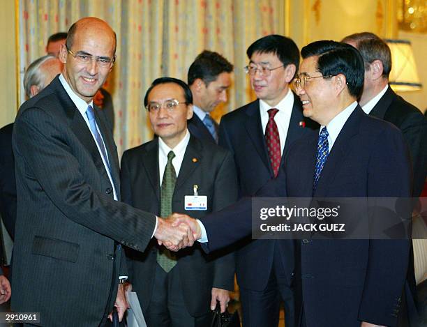 Chinese President Hu Jintao shakes hands with Alstom CEO Patrick Kron 28 January 2004 as they arrive for a meeting with French investors in Paris. Hu...