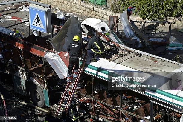 Israeli rescue workers cut apart the blown back roof of a passenger bus shortly after it was torn apart in a suicide attack January 29, 2004 in...