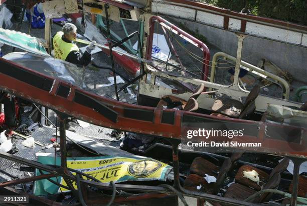 An Israeli rescue worker clears away debris from inside a passenger bus shortly after it was torn apart in a suicide bomb attack January 29, 2004 in...