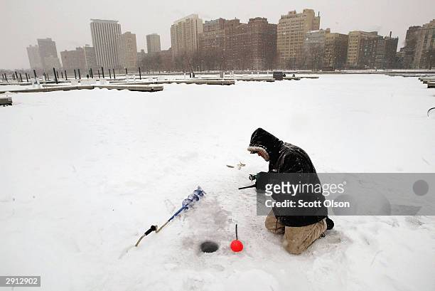 Rudy Manzanunez braves bitter temperatures while ice fishing in Belmont Harbor on Lake Michigan January 29, 2004 near downtown Chicago, Illinois....